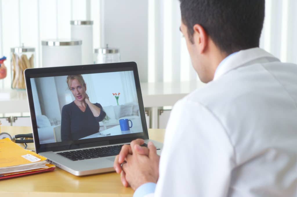 Mexican doctor video chatting with elderly patient